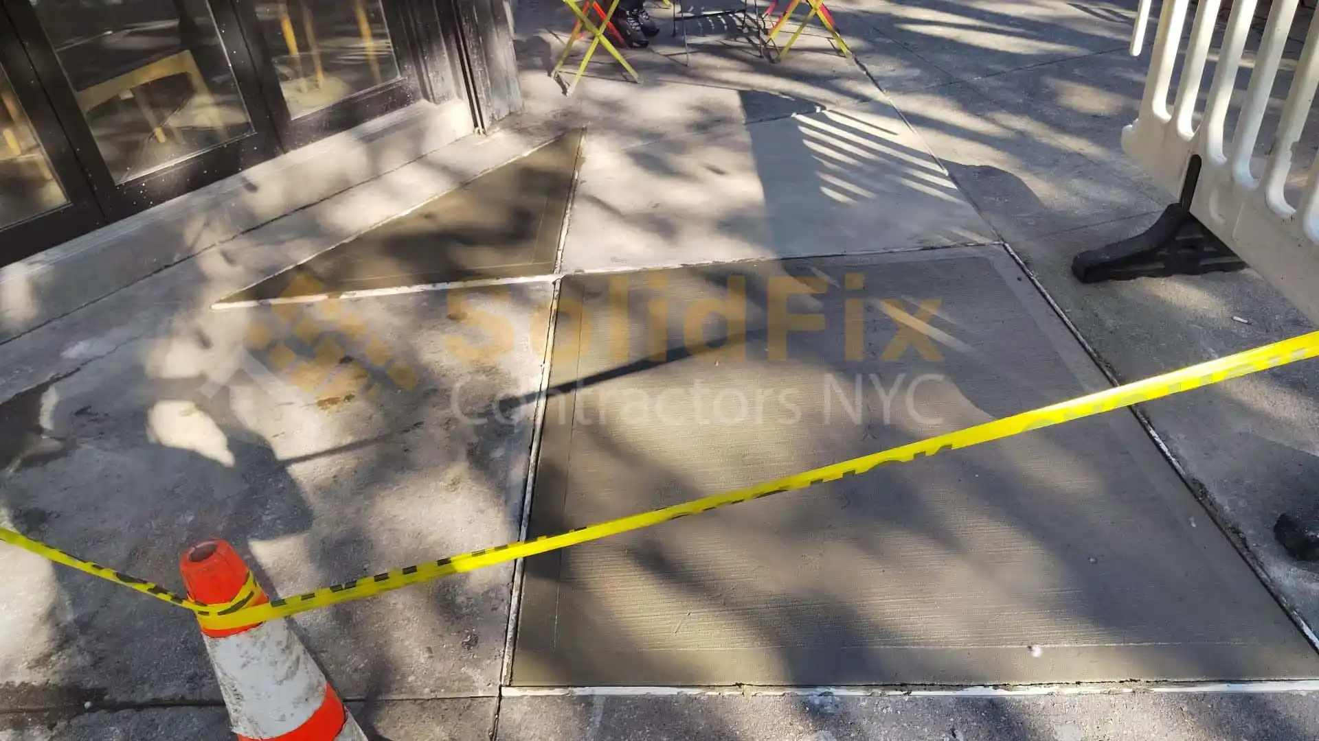 Contractor repairing a cracked sidewalk in a New York City neighborhood
